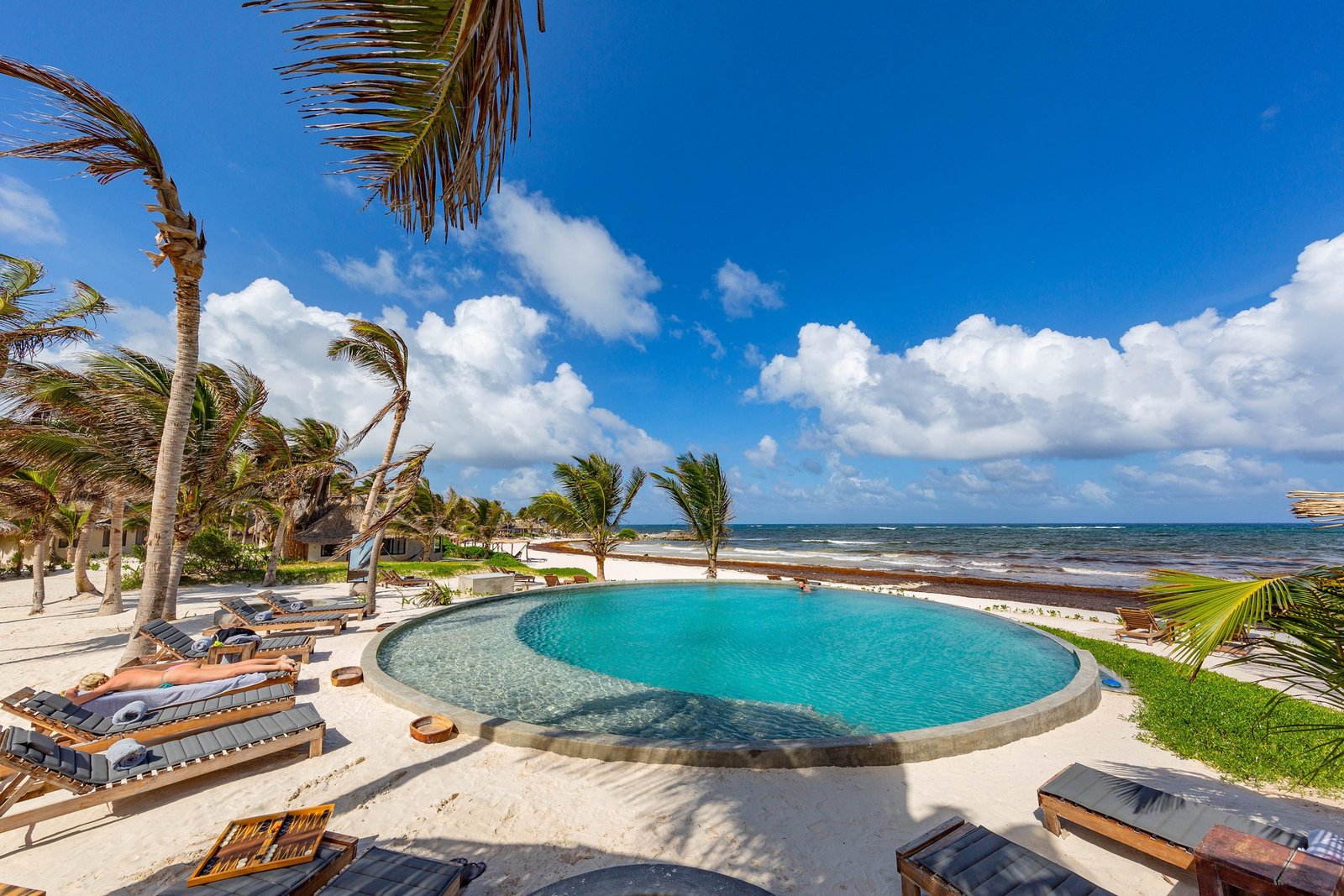 Vista desde el interior de Maya Tulum hacia el mar Caribe, con un mini cenote rodeado de vegetación en primer plano